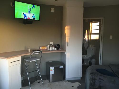 a room with a desk and a tv on the wall at A Stone's Throw Accommodation in Grahamstown