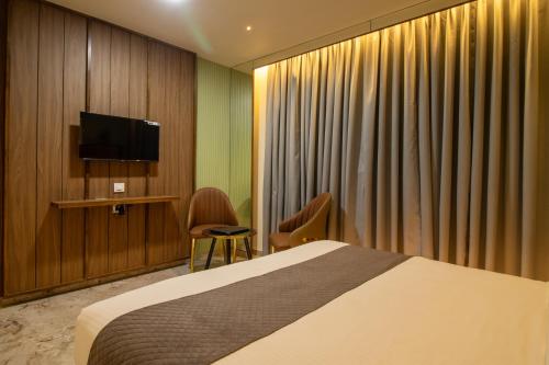 a hotel room with a bed and a flat screen tv at Hotel Ratna Paradise Thane West in Thane