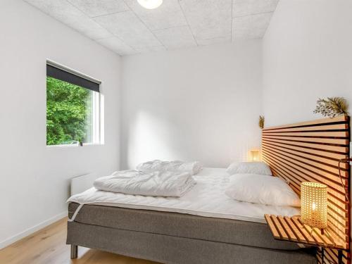 a white bedroom with a large bed and a window at Holiday Home Kiro - 3km from the sea by Interhome in Toftlund