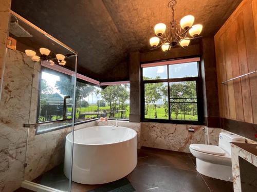 a large bathroom with a large tub and a toilet at Bantunglom Resort in Mae Rim