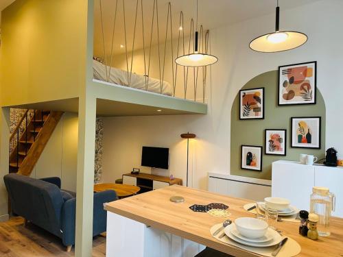 a living room with a dining table and a loft at Forest - Nid au coeur de Fougères in Fougères