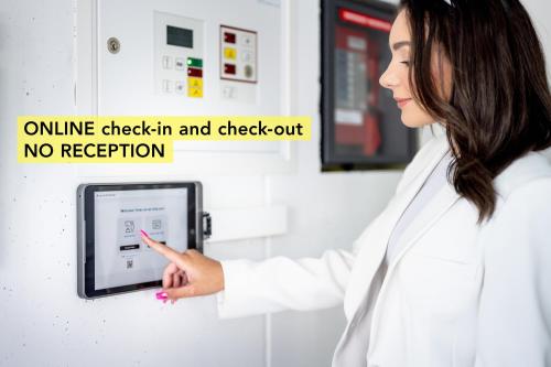 a woman in a white lab coat pointing at a monitor at Anstatthotel Goldau - self-check-in in Goldau
