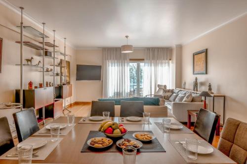 a dining room and living room with a table with food at Lux Apt in Priv Condo with Pool, near Beach, Parking & Easy Access to Lisbon in Parede