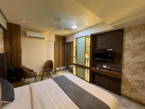a hotel room with a bed and a flat screen tv at Hotel Ratna Paradise Thane West in Thane