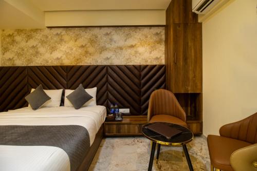 a hotel room with two beds and a chair at Hotel Ratna Paradise Thane West in Thane