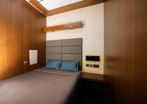 a small bedroom with a bed with blue pillows at Sleepover Terminal 3, Concourse A - formerly sleep 'n fly in Dubai