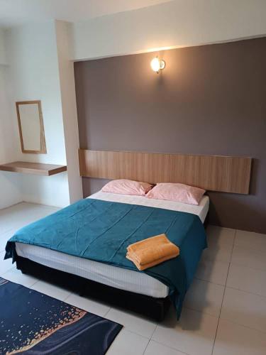 a bedroom with a bed with blue sheets and pink pillows at Lumut Valley in Lumut