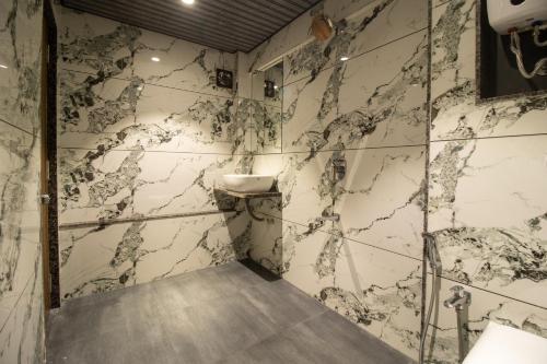 a bathroom with marble walls and a sink at Hotel Ratna Paradise Thane West in Thane