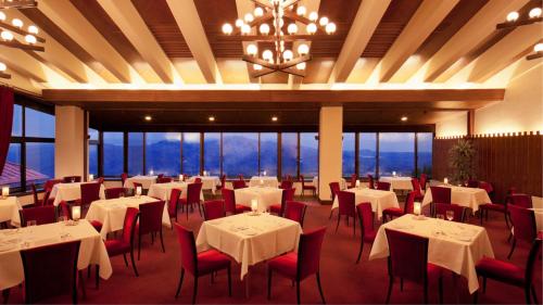 a dining room with tables and chairs and a chandelier at Akakura Kanko Hotel in Myoko