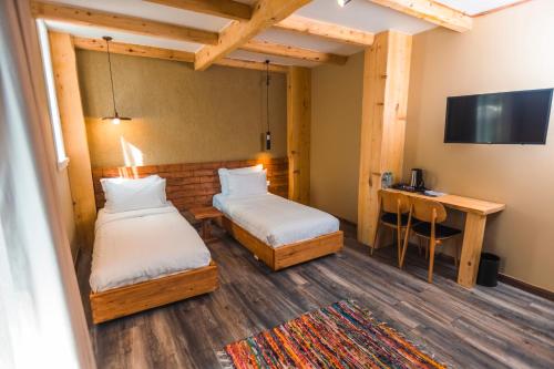 a room with two beds and a desk and a television at Ura e Kovacit Agrotourism in Voskopojë