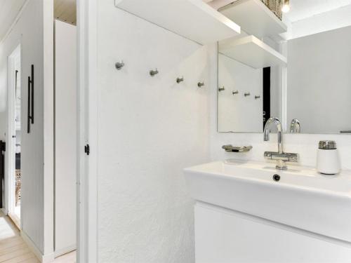 a white bathroom with a sink and a mirror at Holiday Home Judyta - 1km from the sea by Interhome in Fanø