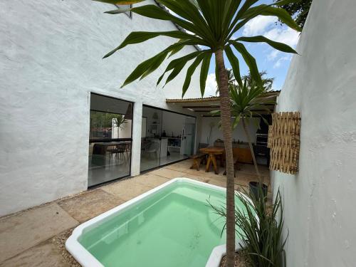 a pool with a palm tree next to a house at Casa Branca Mediterrânea in Barra Grande