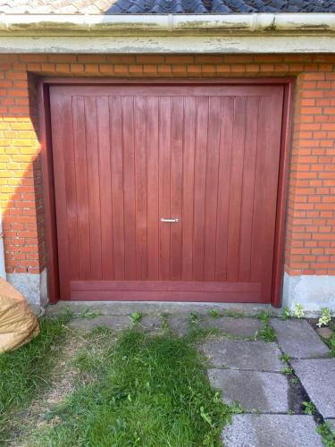 a red garage door on a brick building at Flot hus med flot natur in Holeby
