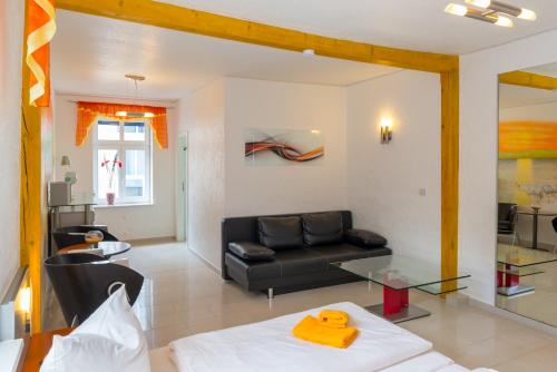 a living room with a black couch and a glass table at Hotel Am Müritzhafen garni in Waren