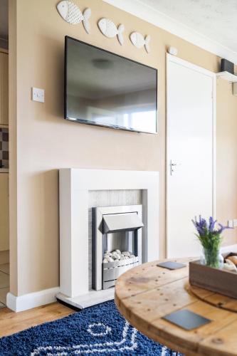 a living room with a fireplace with a tv above it at The Phoenix by the Sea- 2 bedroom flat in hunny in Hunstanton