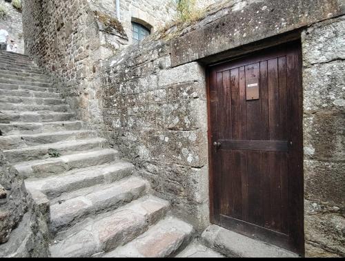 a wooden door on a stone building with stairs at Chez Adèle in Le Mont Saint Michel