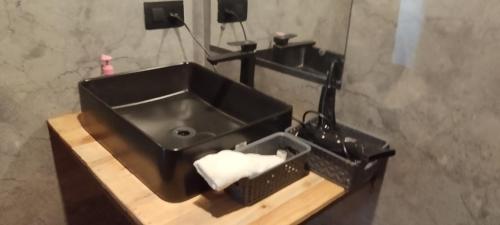 a bathroom with a black sink and a basket of towels at Dunewood villa in Jaipur