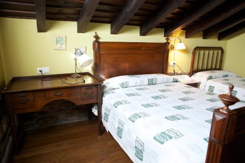 1 dormitorio con 2 camas y escritorio con lámpara en Apartamentos Rurales Colsa, en Colsa