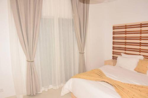Un dormitorio con una cama y una ventana con cortinas. en Nenuphar, en Dakar