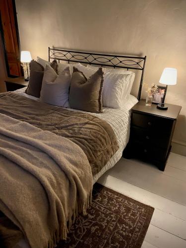 een slaapkamer met een groot bed met kussens bij Poets Cottage Eglwys Fach in Eglwys-fach