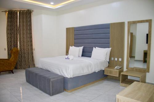 a bedroom with a large bed with a blue headboard at Uniglobe Hotel and Apartments in Gwarinpa