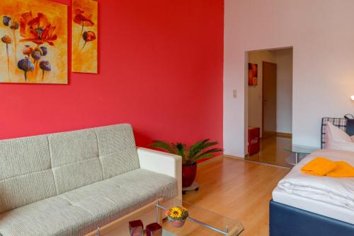 a living room with a couch and a red wall at Hotel Am Müritzhafen garni in Waren
