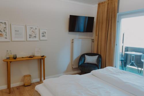 a bedroom with a bed and a chair and a television at Haggn&Co in Neukirchen