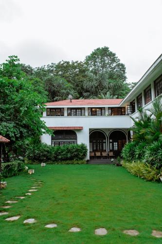 a large white building with a green yard at Viraam Estate by RÊVE in Assagao