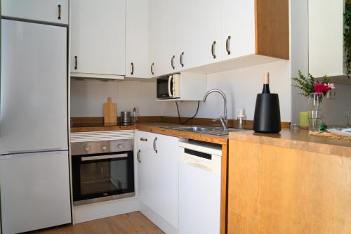 a kitchen with white cabinets and a sink at Piso Luminoso A Metros De La Plaza De Las Flores in Murcia