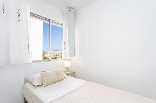 Un dormitorio blanco con una cama y una ventana. en Spacious 3-Bedroom Apartment with Pool & Balcony - Steps from Puerto Colón, Beach & All Local Attractions, en Adeje