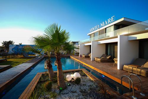a building with a swimming pool with palm trees in front of it at VENTO MARE LUXURY Hotel in Cesme