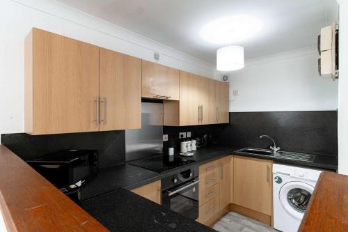 a kitchen with wooden cabinets and a black counter top at Lovely 1 Bed Harbour-side Apartment - Sea Views in Whitehaven