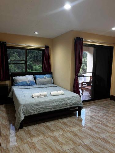 a bedroom with a bed with two towels on it at Rattana's Resort in Ranong