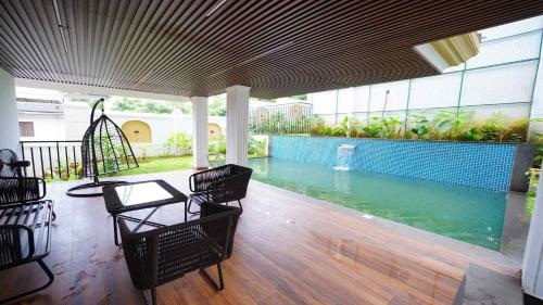 a patio with a table and chairs and a swimming pool at Villa Paraiso by DanCenter | 4BHK Pvt Pool | Arpora in Goa