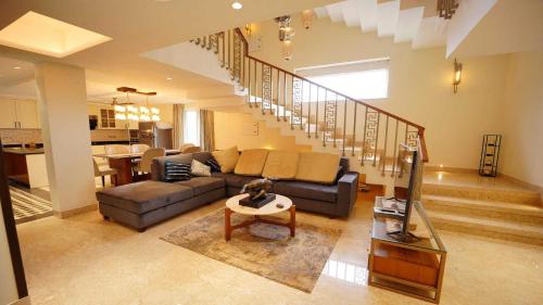 a living room with a couch and a staircase at Villa Paraiso by DanCenter | 4BHK Pvt Pool | Arpora in Goa