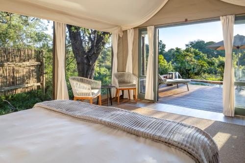 a bedroom with a bed and a balcony with a view at Simbavati River Lodge in Timbavati Game Reserve
