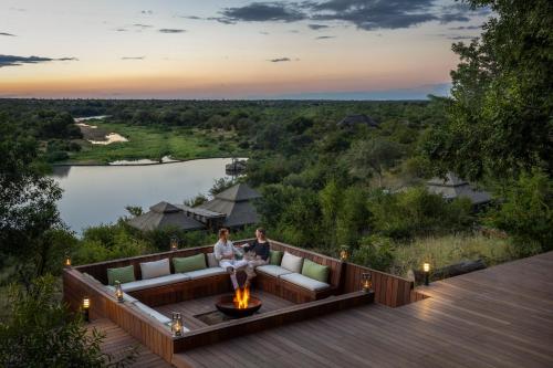 two people sitting on a couch on a deck with a fire pit at Simbavati Hilltop Lodge in Timbavati Game Reserve