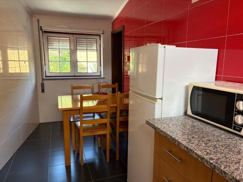 una cucina con un frigorifero bianco e un tavolo con sedie di Recanto do Açor a Vide