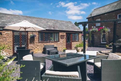 a patio with a table and chairs and an umbrella at Wisteria Cottage Wye Valley AONB in Llangarren