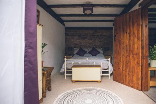 ein Schlafzimmer mit einem Bett und einer Ziegelwand in der Unterkunft Wisteria Cottage Wye Valley AONB in Llangarren