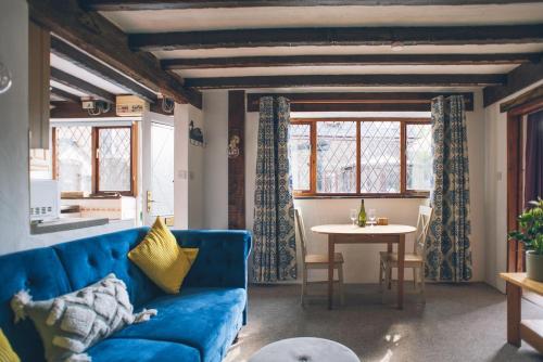 ein Wohnzimmer mit einem blauen Sofa und einem Tisch in der Unterkunft Wisteria Cottage Wye Valley AONB in Llangarren