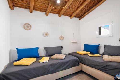 two beds in a room with blue and yellow pillows at Casa Gotinha d' Água in Alcaria Ruiva