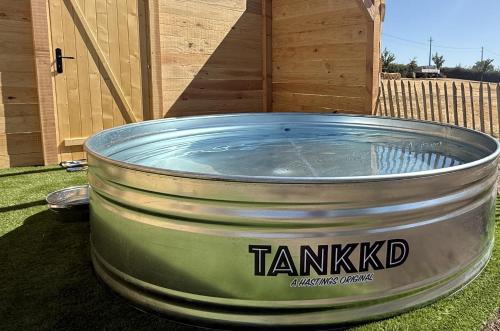 a large metal tub filled with water sitting on the grass at La Cachette du Domaine du Moulin avec son spa privé en option in Saint-Laurent-dʼAndenay