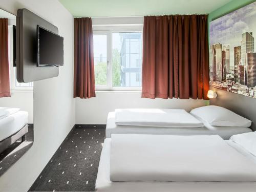 a hotel room with two beds and a flat screen tv at B&B Hotel Frankfurt-West in Eschborn