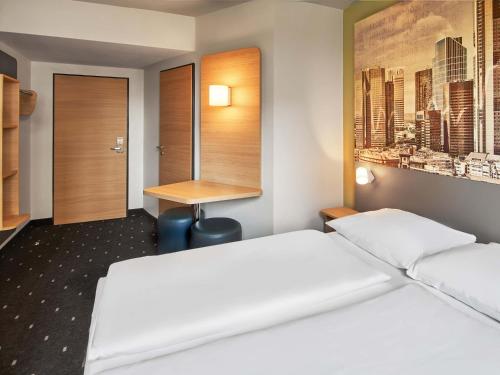 a hotel room with two beds and a desk at B&B Hotel Frankfurt-West in Eschborn
