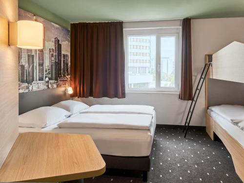 a hotel room with two beds and a window at B&B Hotel Frankfurt-West in Eschborn
