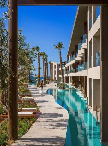 a resort swimming pool with palm trees and buildings at Nalu Resort & SPA Adults Only Hotel in Adelianos Kampos