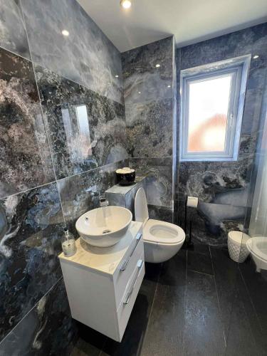 a bathroom with a sink and a toilet and a window at House in Watford