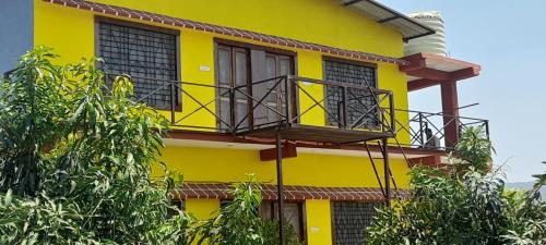 ein gelbes Gebäude mit einem Balkon darauf in der Unterkunft Mountain View Farmstay in Matkuli