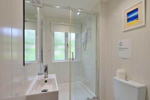ein weißes Badezimmer mit Dusche und Waschbecken in der Unterkunft Finest Retreats - Joyful Cottage in Saint Erth